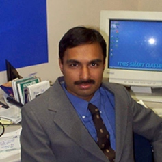 Undergraduate Program Director, Srinivasan Balaji, sitting at his desk in a grey suit and blue shirt