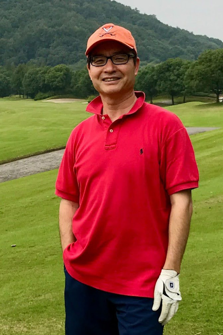 Feifang Hu in a red polo shirt and golfing glove on a green lawn