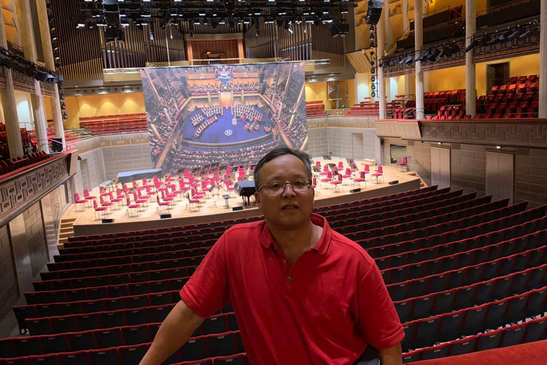 Hua Liang in a large empty theater with a stage in the background