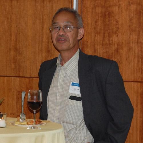 Professor of Statistics, Zhaohai Li, in a gray suit with a white shirt at a standing table